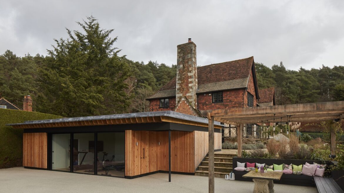 Luxury pool house exterior with wood cladding and a living grass roof, integrated into garden design.