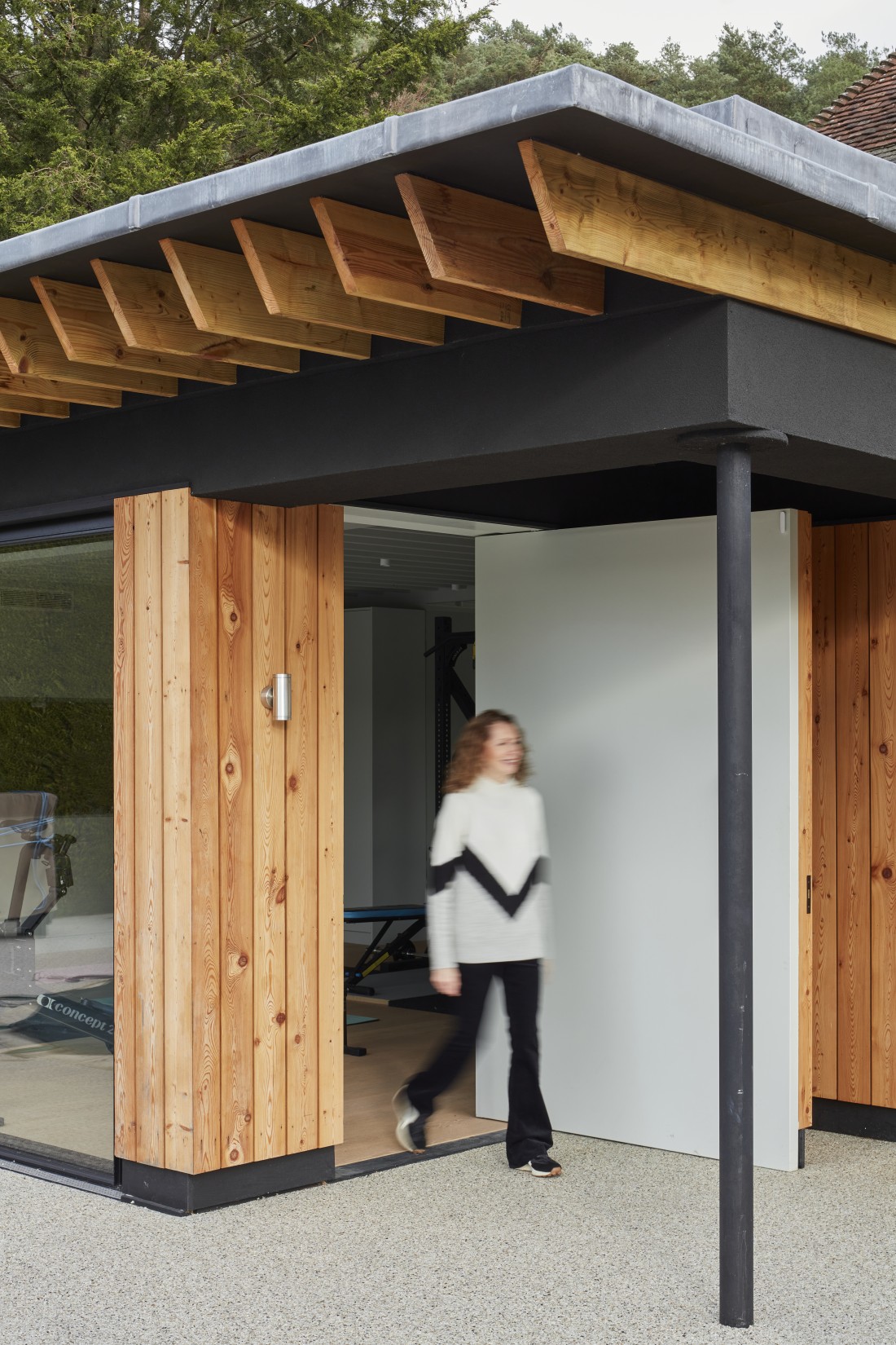 Pool house with wood cladding and modern design at Surrey Manor House, entrance view.