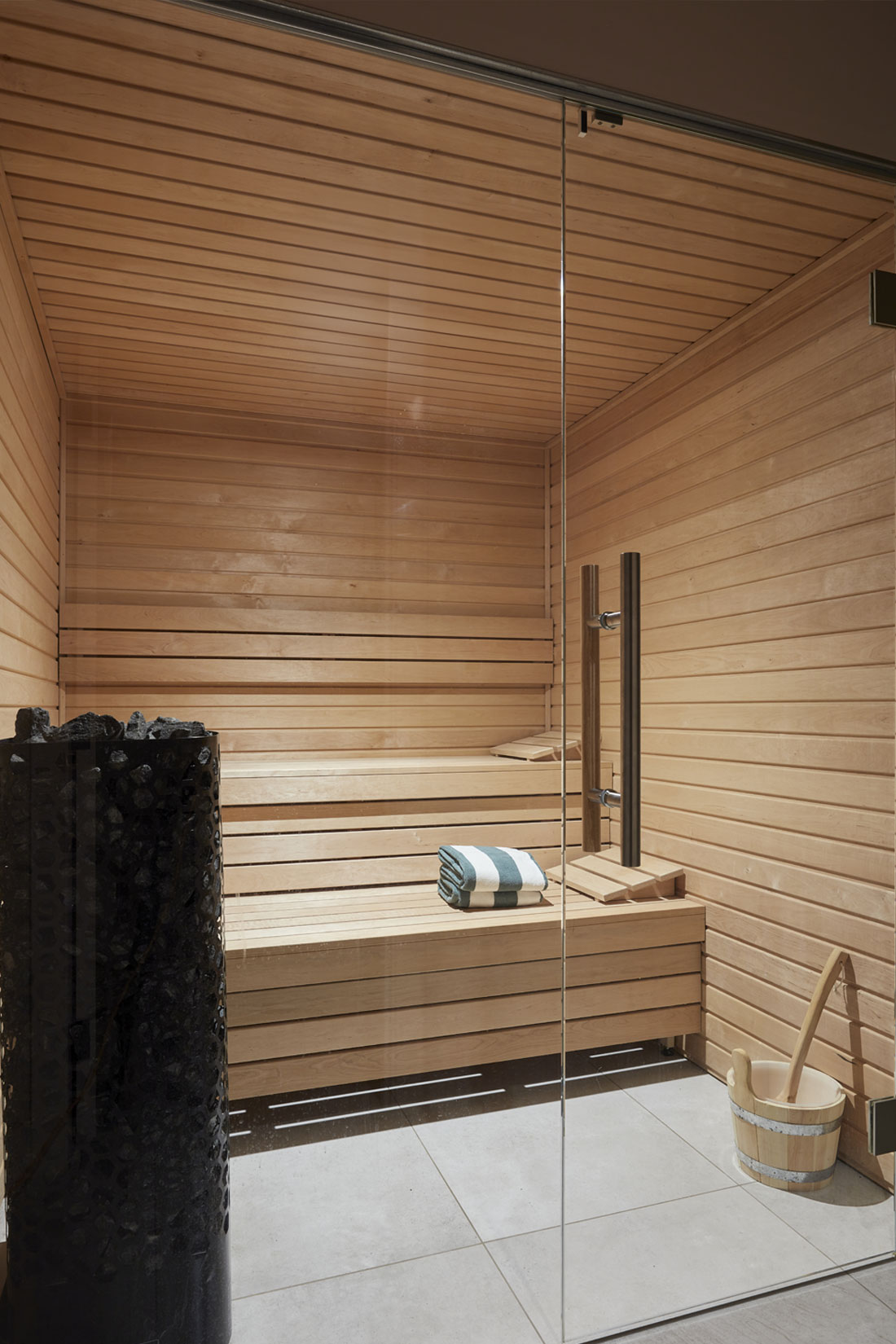 Pool house sauna with wooden interiors and glass doors for luxury relaxation.