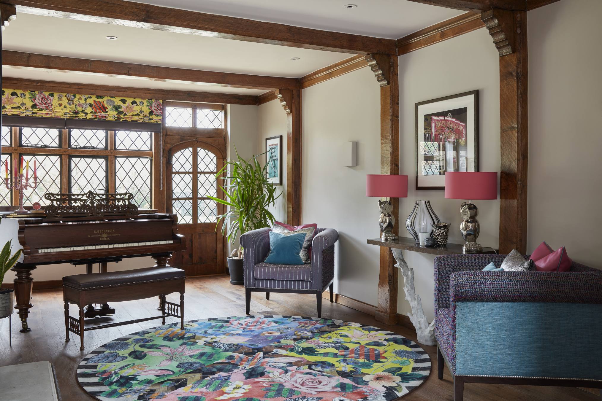 Grand entrance hall in a Surrey manor house featuring a cherished piano and a vibrant circular rug.