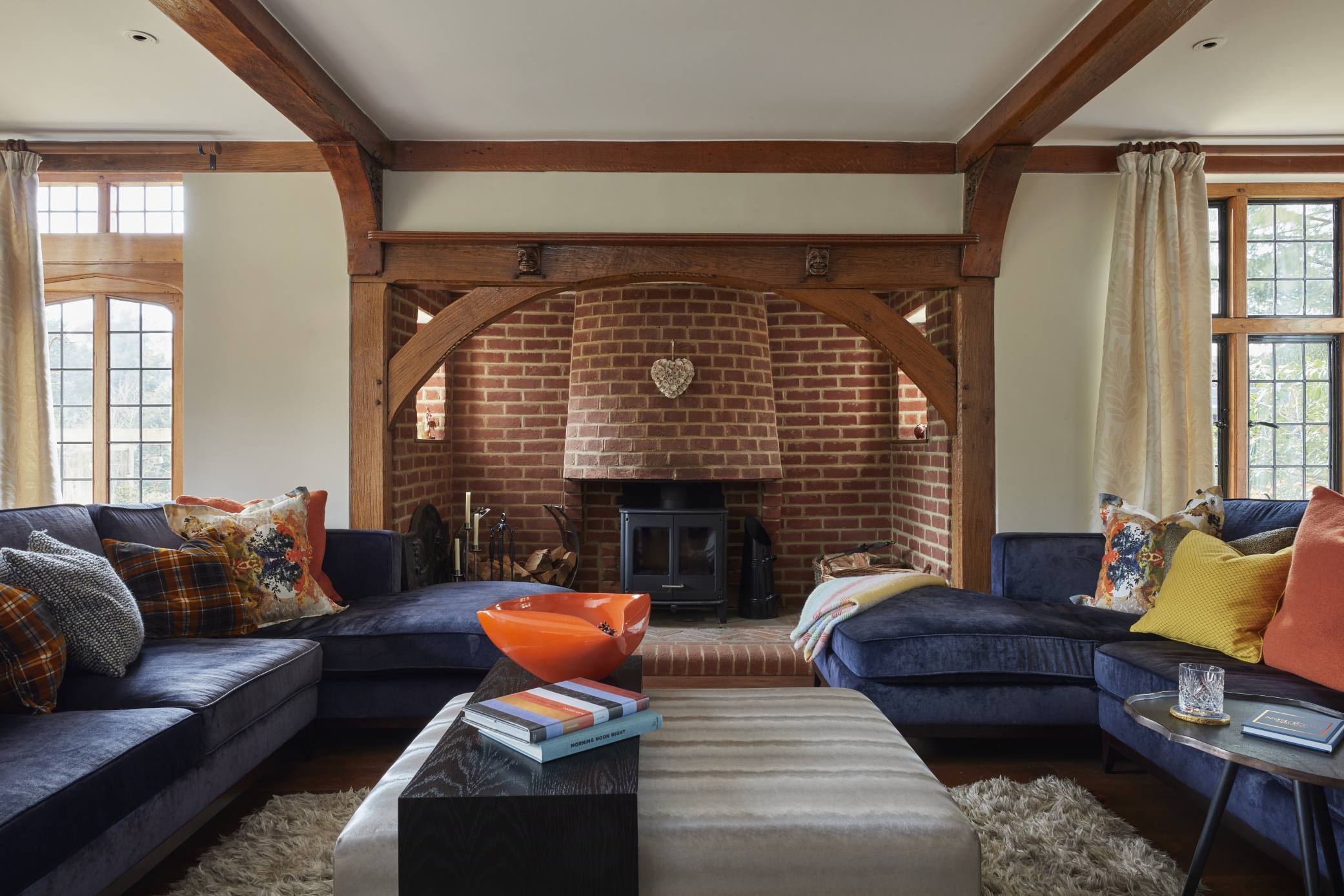 Luxury living room in a Surrey manor house with exposed brick fireplace and plush blue seating.