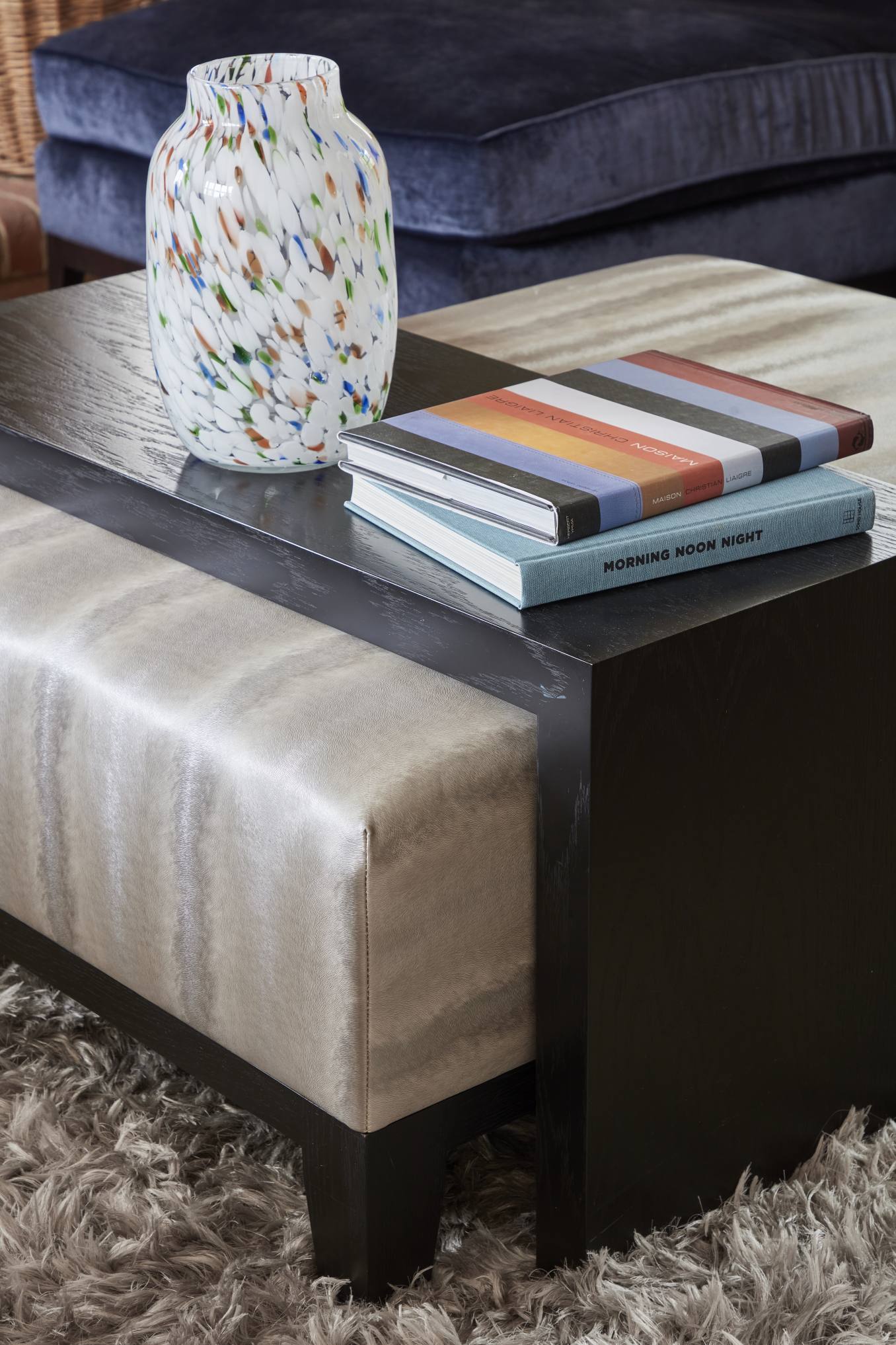 Designer coffee table with curated books and an artisan glass vase in a Surrey luxury home.