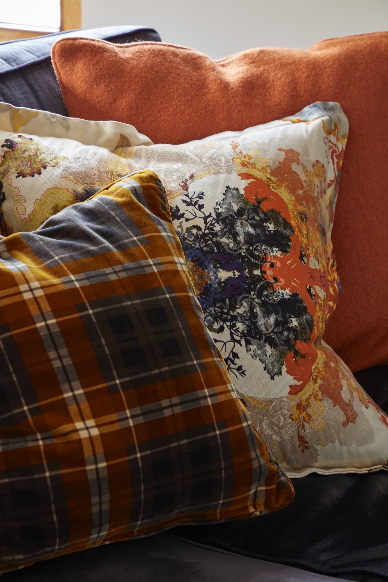 Luxurious mix of plaid and patterned cushions in a Surrey manor house living room.