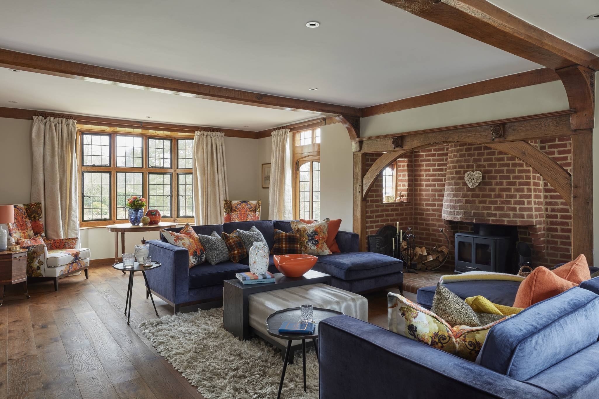 Spacious living room in a luxury Surrey manor house with exposed beams and rich textures.