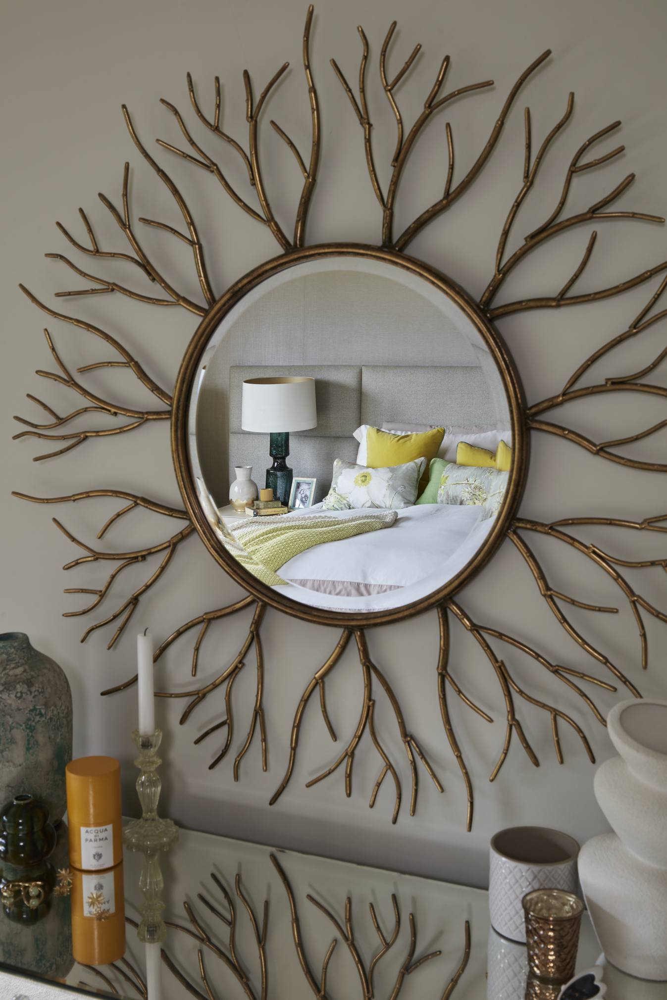 Sunburst mirror reflecting the plush bed and elegant bedroom styling.