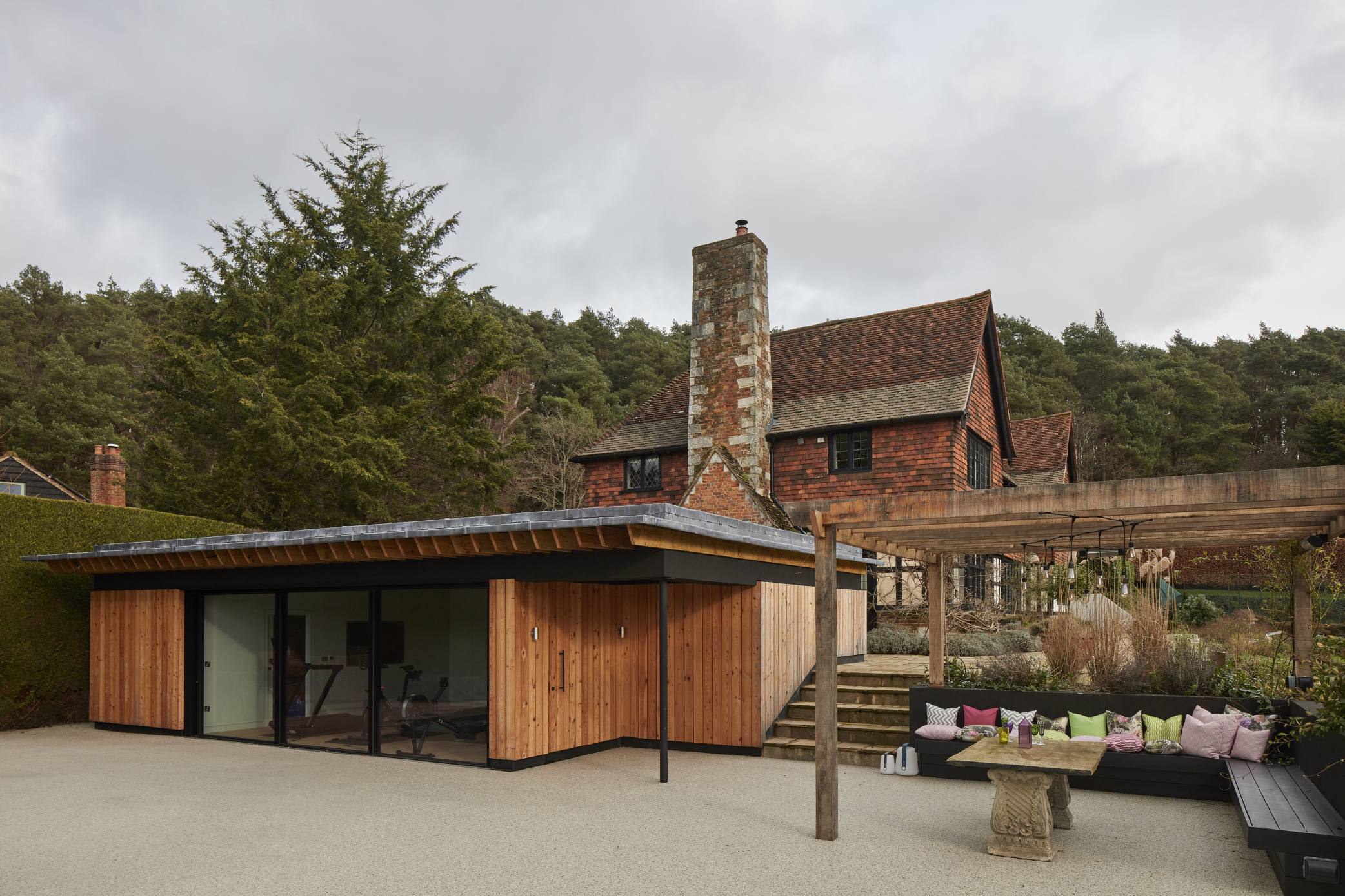 Full view of the pool house with an outdoor lounge and the main house in the background