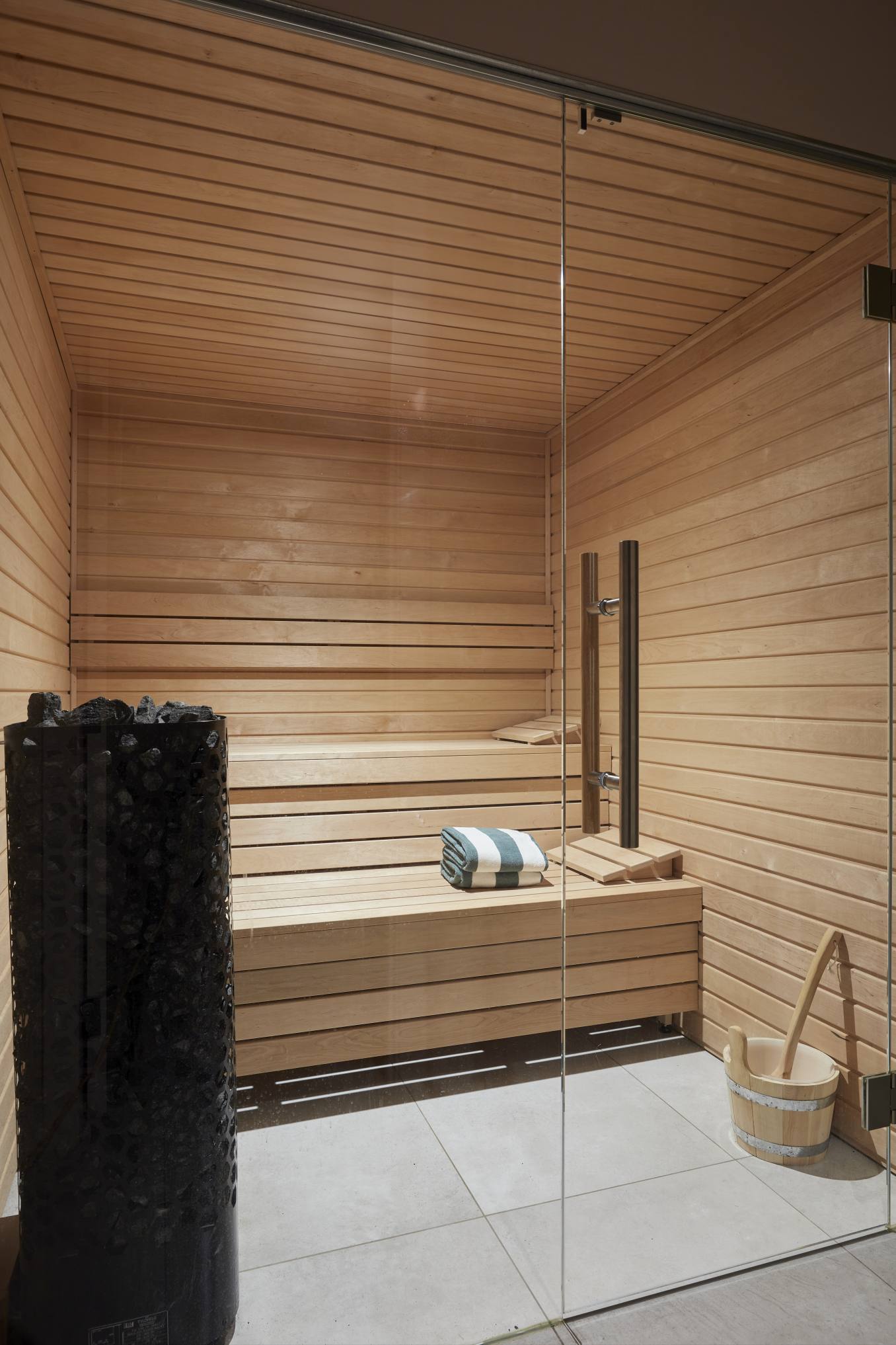 Custom-built wooden sauna in the pool house with a glass front